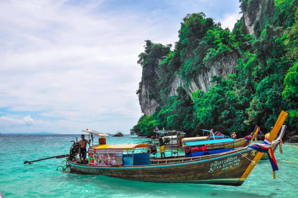 Ein Longtailboot vor Kalksteinfelsen im Meer vor Krabi in Thailand